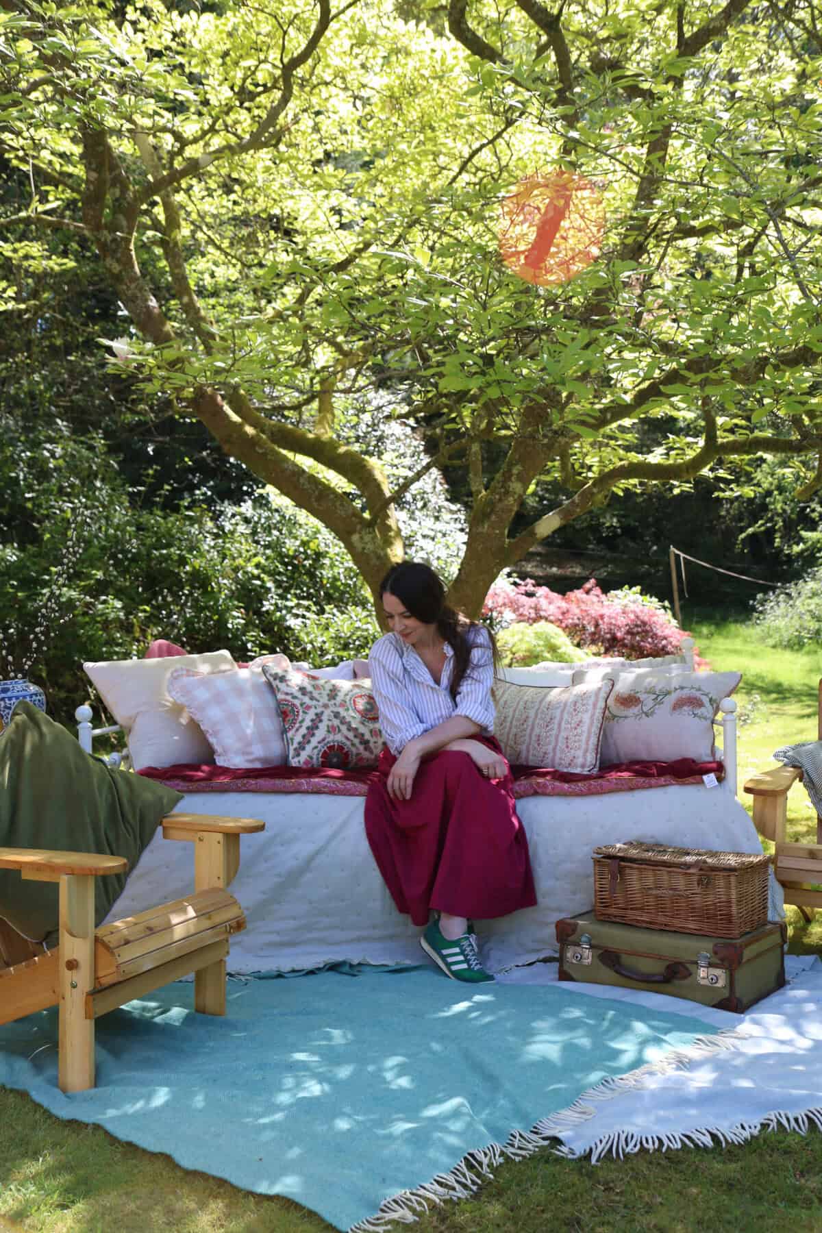 Cherry Menlove sitting on her day bed in her sunny english cottage garden